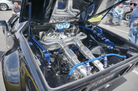 1995 Ford Taurus - A highly customized engine bay with polished chrome exhaust pipes and bright blue bracing is displayed with the hood open.