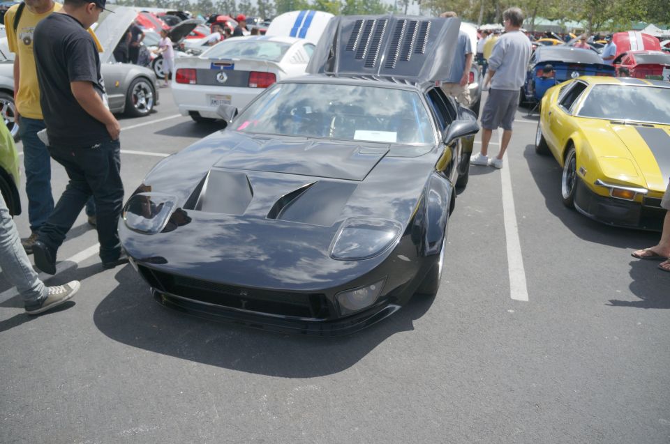 Black sports car with hood and engine cover open, parked next to a yellow sports car