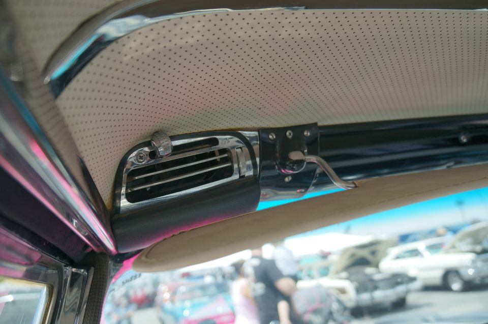 Interior view of a car's air vent and grab handle with other vehicles visible outside