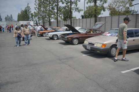 1995 Ford Taurus - A tan sedan is parked in a lot with other cars and people.