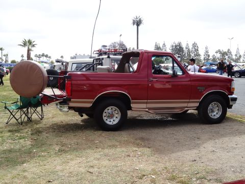 1994 Ford Bronco - Side view of a red 1994 Ford Bronco, equipped with a rear spare tire carrier and aftermarket wheels.