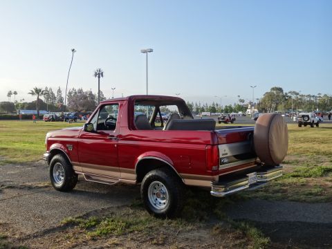 1994 Ford Bronco - This red 1994 Ford Bronco features a tan accent stripe and a spare tire mounted on the rear tailgate.