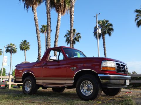 1994 Ford Bronco - This 1994 Ford Bronco is parked on grass with palm trees and a clear blue sky overhead.