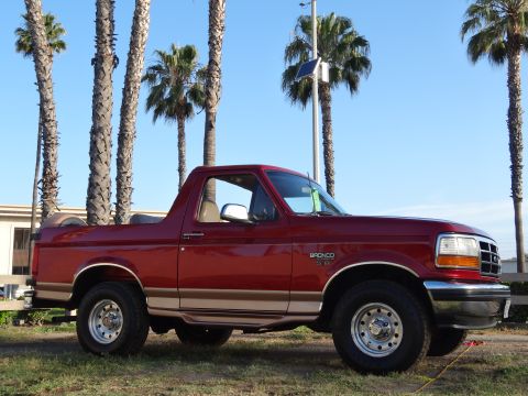1994 Ford Bronco - A red 1994 Ford Bronco is seen from the front three-quarter angle, parked outdoors.