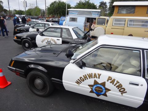 1994 Ford Bronco - Several California Highway Patrol cars are parked in a lot, with other vehicles and people in the background.