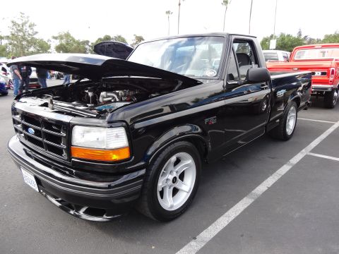 1994 Ford Bronco - Black 1994 Ford F-150 pickup truck with hood open, parked next to a red truck.