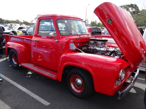 1994 Ford Bronco - A bright red 1956 Ford F-100 pickup truck is displayed with its hood open, revealing a chrome engine.