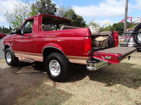 1994 Ford Bronco - Red 1994 Ford Bronco with tailgate down, parked outdoors with another vehicle visible in the background.