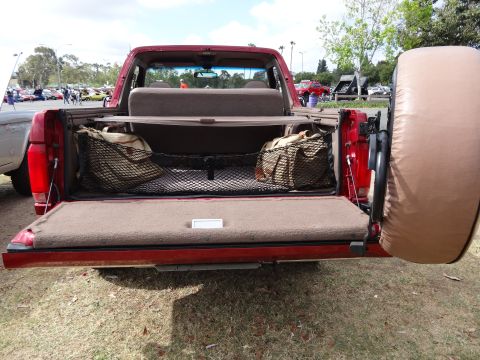 1994 Ford Bronco - This 1994 Ford Bronco's tailgate is open, revealing storage nets and bags, with a spare tire cover mounted externally.