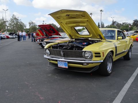 1994 Ford Bronco - A yellow 1970 Ford Mustang Boss 302 is displayed with its hood open at an outdoor car show.