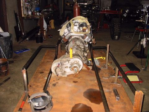 1994 Ford Bronco - An engine and transmission assembly is mounted on a custom stand in a cluttered garage setting.