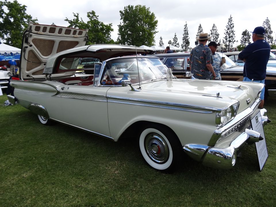 Cream 1959 Ford Fairlane 500 Skyliner with its hardtop roof raised, parked on grass