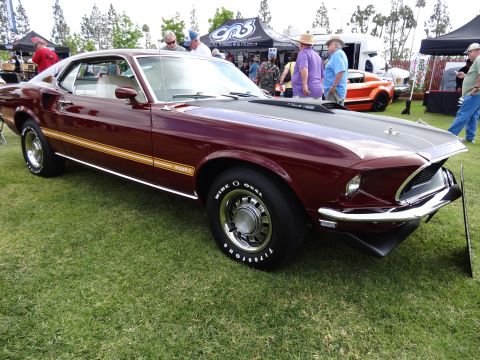 1994 Ford Bronco - A classic maroon 1969 Ford Mustang Mach 1 is displayed outdoors with people and tents in the background.