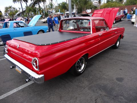 1994 Ford Bronco - A red 1964 Ford Falcon Ranchero is parked next to a blue pickup truck at an outdoor car show.