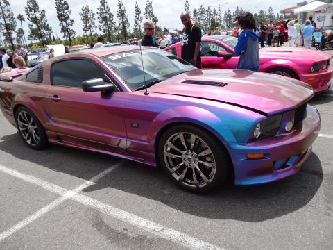 1994 Ford Bronco - A custom Ford Mustang with a color-shifting paint job is displayed at an outdoor event.