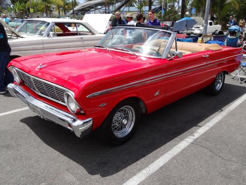 1994 Ford Bronco - A classic red convertible is parked at an outdoor event, with another vintage car beside it.