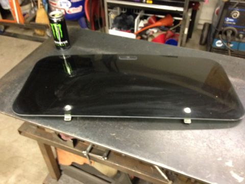 1987 Suzuki Samurai - A black sunroof panel rests on a workbench, with a Monster Energy can in the background.