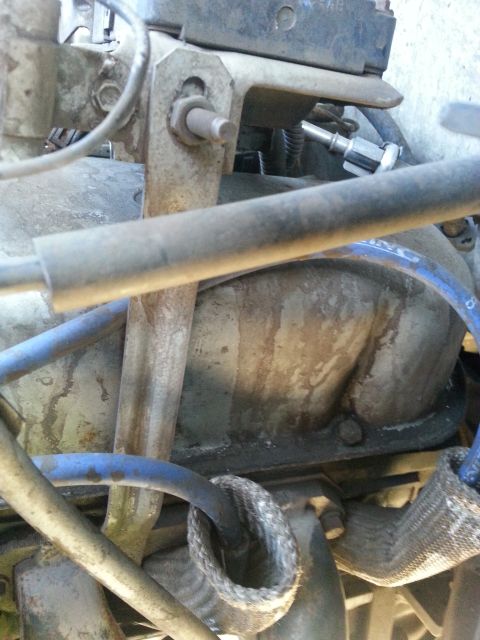 1992 Ford Bronco - Close-up view of engine components, including hoses and metal brackets, with visible oil stains.