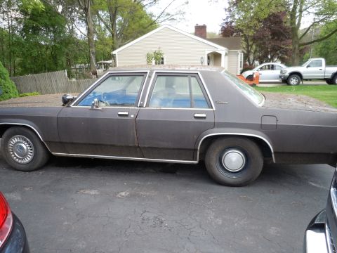 2001 Ford Crown Victoria - Side profile of a classic Ford sedan, likely from the 1980s, parked outdoors.
