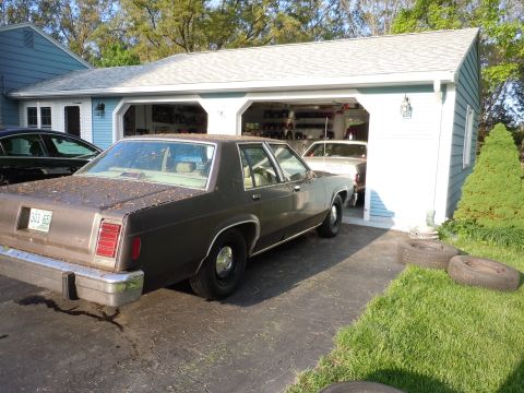 2001 Ford Crown Victoria - A brown 1980 Ford LTD Crown Victoria is parked in a driveway next to a garage with another vehicle inside.