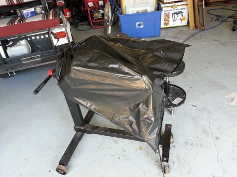 1994 Ford Bronco - An engine covered in plastic sits on a stand, with a golf cart visible behind it.