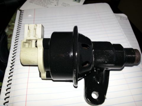 1994 Ford Bronco - This black automotive part features a white electrical connector and a threaded end, resting on a notebook.
