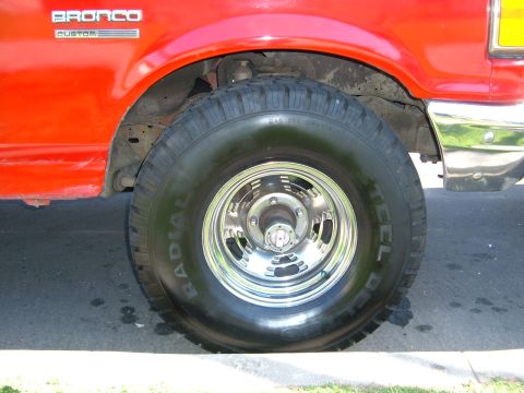 1988 Ford Bronco - Close-up of the front wheel and fender of a red 1988 Ford Bronco Custom.