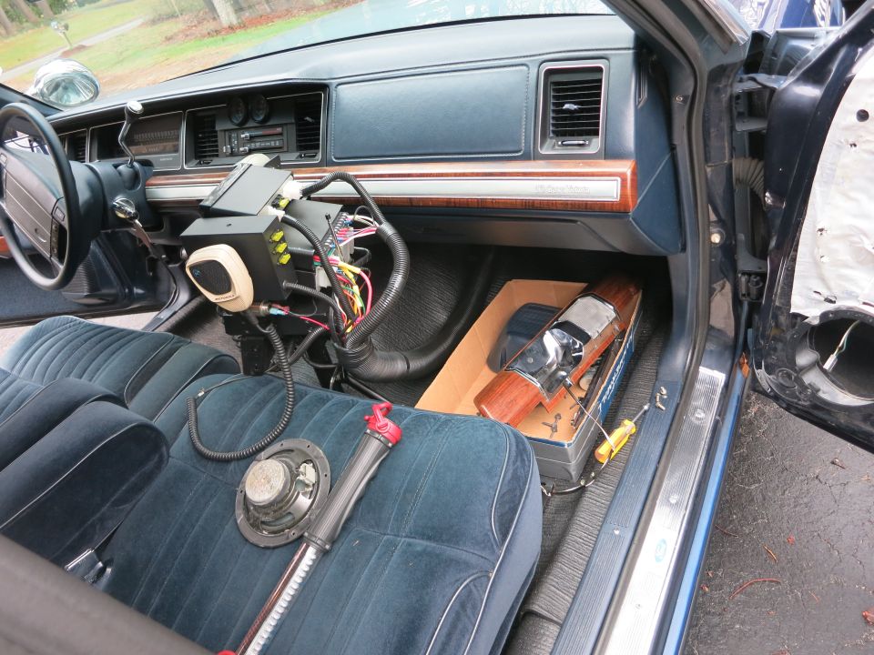 Interior of a police car, showing the dashboard, steering wheel, and passenger seat with wiring and equipment