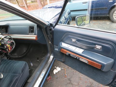 1991 Ford LTD Crown Victoria - The interior of a 1991 Ford Crown Victoria LTD, with the driver's door open, revealing the door panel and dashboard. Another vehicle is vis…