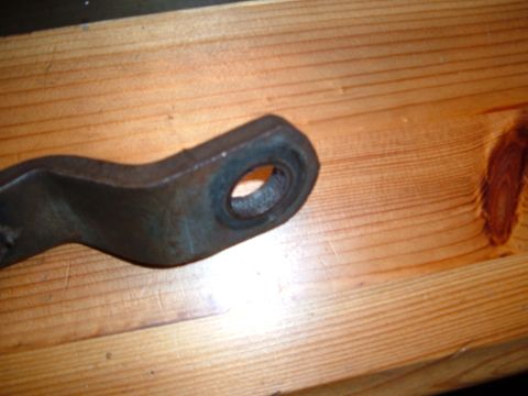 1988 Ford Bronco - A metal bracket with a circular opening rests on a wooden surface, with the Supermotors.net logo in the lower right corner.