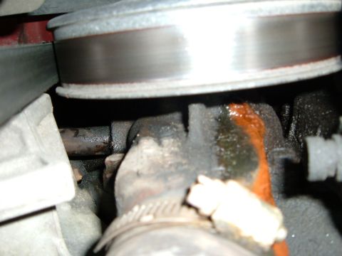 1988 Ford Bronco - Engine part showing a leak of orange fluid, with a metal pulley above.