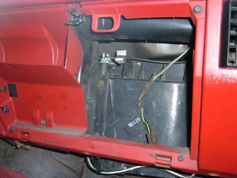 1988 Ford Bronco - Close-up of the interior of a vehicle, showing red dashboard trim and exposed HVAC components with visible wiring and a part number.