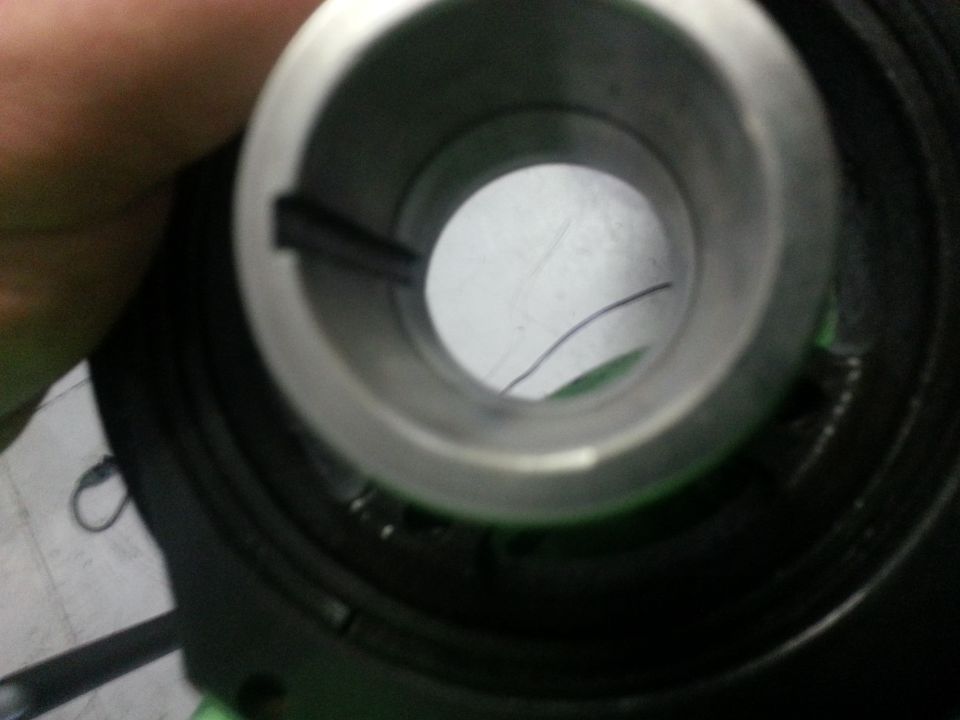 Close-up of a metal engine part with a slot and a wire inside