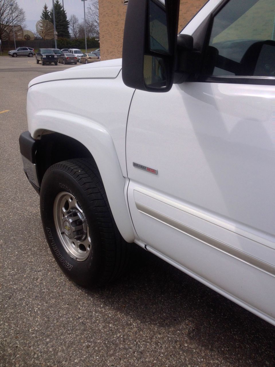 White 2006 Chevrolet Silverado 2500 pickup truck, front quarter view showing fender, wheel, and door trim