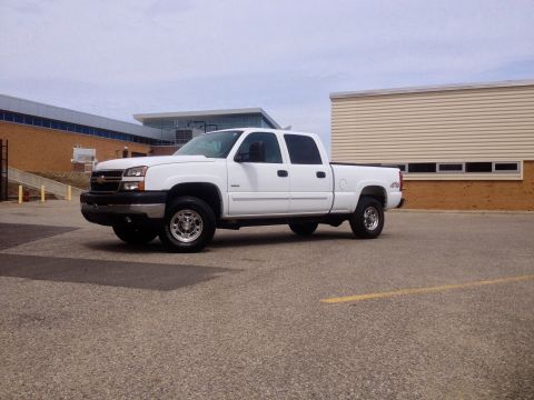 2006 Chevrolet Silverado 2500 - A white Chevrolet Silverado pickup truck is parked in an asphalt lot with a building in the background.