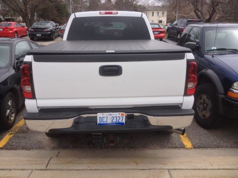 2006 Chevrolet Silverado 2500 - Rear view of a white 2006 Chevrolet Silverado 2500 pickup truck parked between other vehicles.