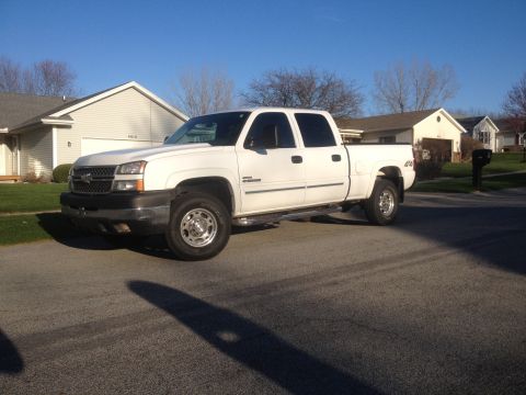 2006 Chevrolet Silverado 2500 - A white 2006 Chevrolet Silverado 2500 pickup truck is parked on a street in front of houses.
