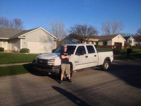 2006 Chevrolet Silverado 2500 - A person poses with a white Chevrolet Silverado 2500 pickup truck parked in a residential driveway on a sunny day.
