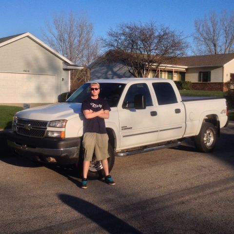2006 Chevrolet Silverado 2500 - A man stands next to a white 2006 Chevrolet Silverado 2500 pickup truck in front of a residential house.