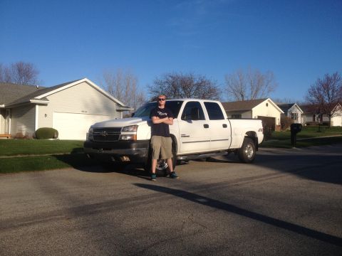 2006 Chevrolet Silverado 2500 - A man poses in front of a white 2006 Chevrolet Silverado 2500 pickup truck on a sunny day.