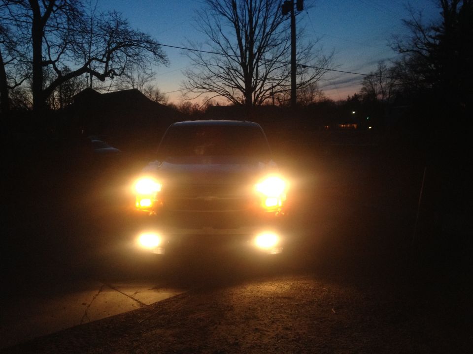 Truck front end with headlights on, dusk sky