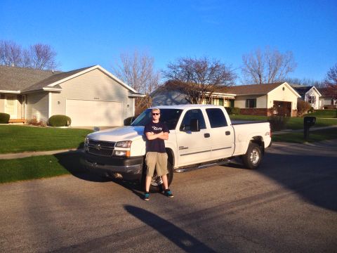2006 Chevrolet Silverado 2500 - A white 2006 Chevrolet Silverado 2500 pickup truck is parked on a residential street with a person standing next to it.