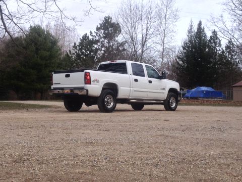 2006 Chevrolet Silverado 2500 - A white 2006 Chevrolet Silverado 2500 pickup truck is parked on a gravel lot with trees in the background.