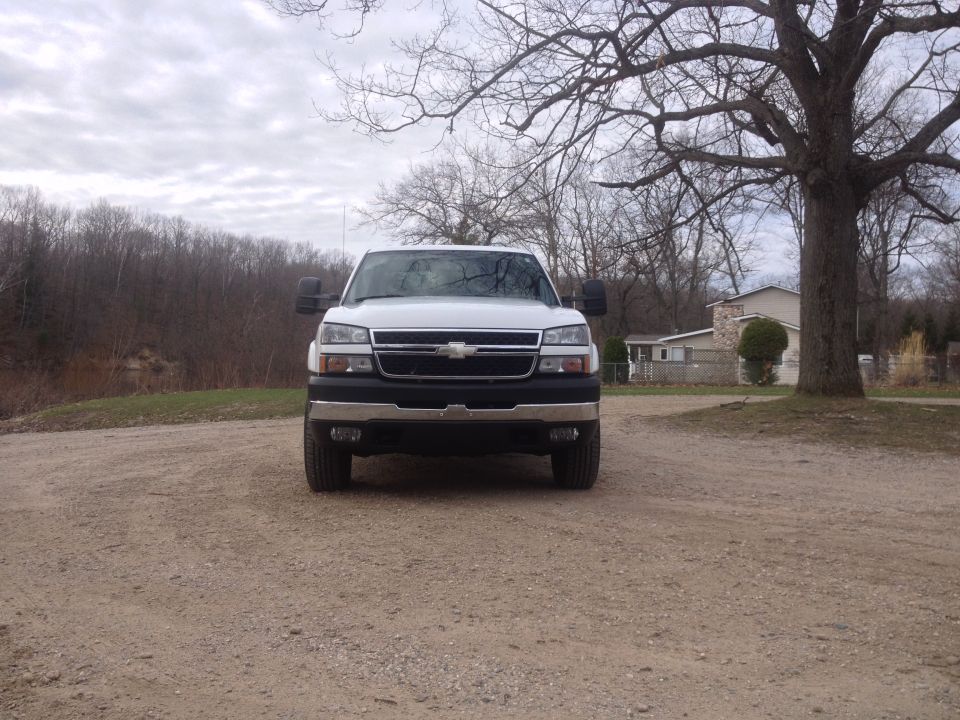 White Chevrolet pickup truck, front view, parked on a dirt road