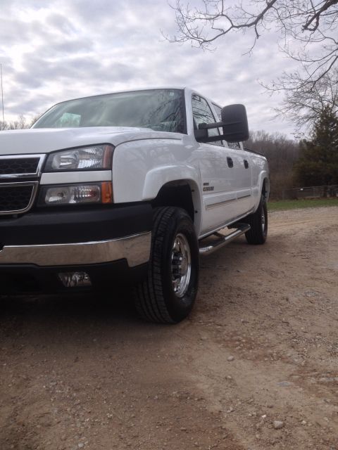 2006 Chevrolet Silverado 2500 - Front quarter view of a white 2006 Chevrolet Silverado 2500 pickup truck on a gravel road under a cloudy sky.