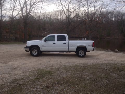2006 Chevrolet Silverado 2500 - Side view of a white 2006 Chevrolet Silverado 2500 pickup truck with a crew cab and long bed, parked outdoors.