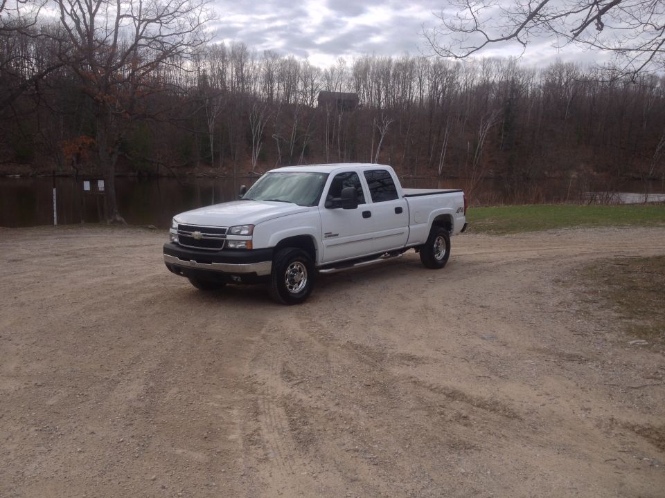 White 2006 Chevrolet Silverado 2500 parked on a dirt road near a body of water