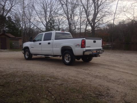 2006 Chevrolet Silverado 2500 - White 2006 Chevrolet Silverado 2500 pickup truck parked on a dirt lot with trees in the background.