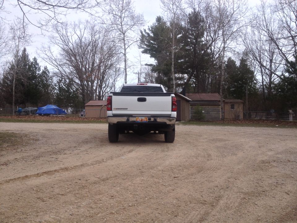 Rear view of a white 2006 Chevrolet Silverado 2500 pickup truck parked on a dirt lot