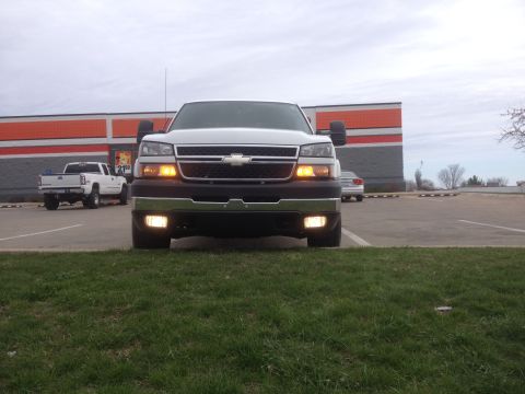 2006 Chevrolet Silverado 2500 - A white Chevrolet Silverado 2500 is parked in front of a building with another truck in the background.